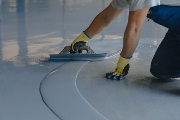A man painting a floor with a roller, representing an epoxy flooring service in Washington, DC.