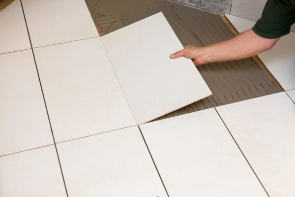 A man engaged in tile installation on a bathroom floor, illustrating a tile flooring service in Washington, DC.